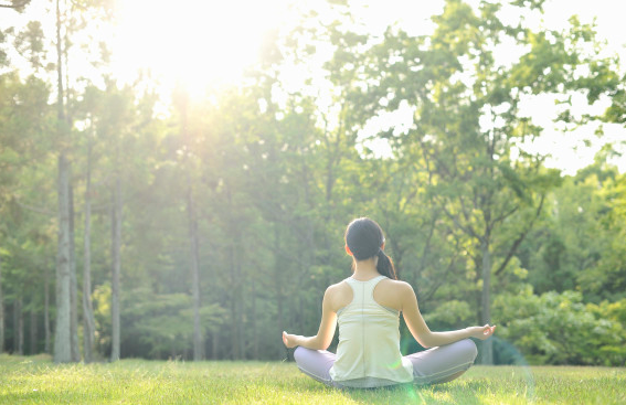 A person meditating outdoors in a green park